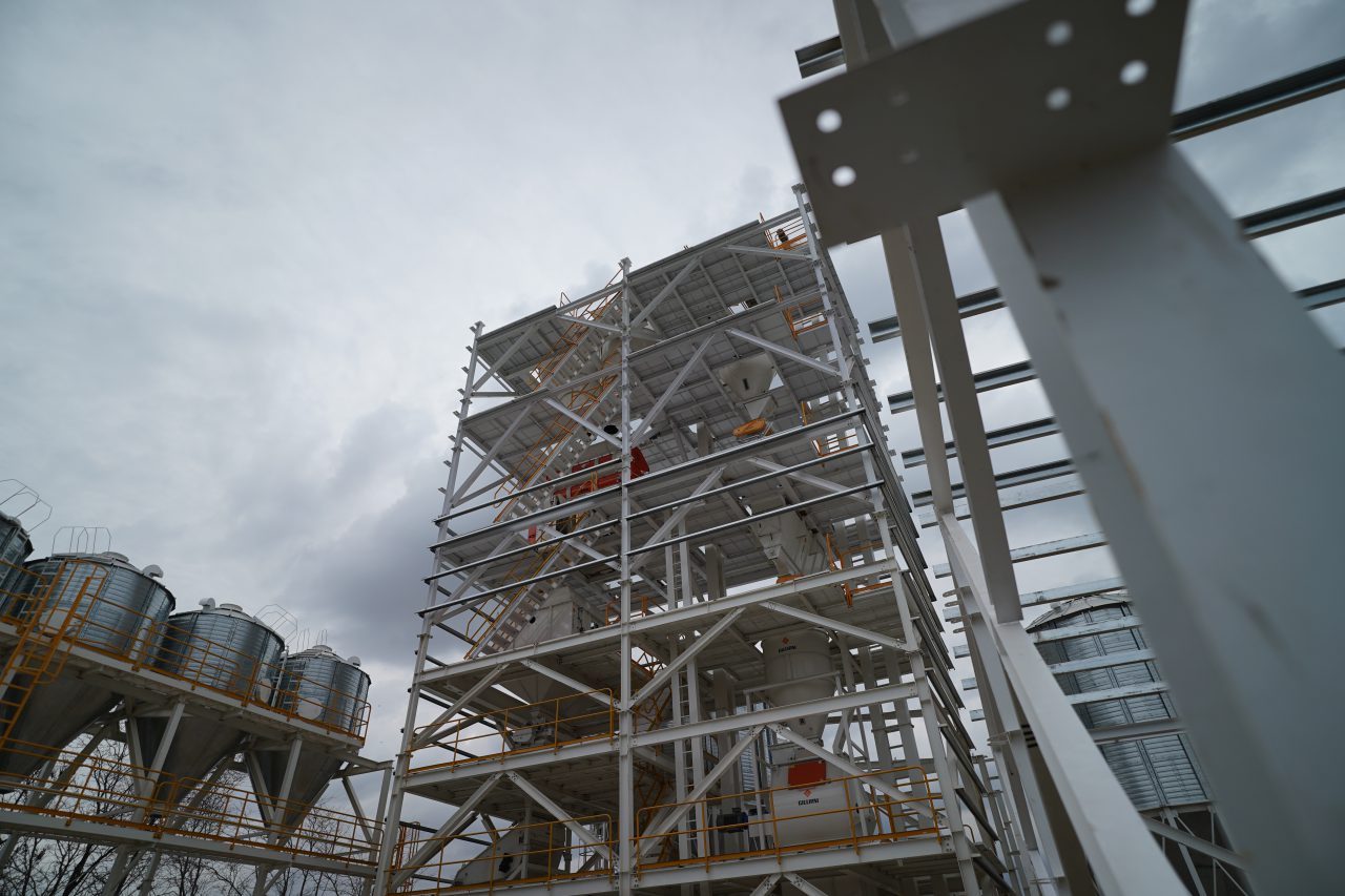 Estructura exterior de una planta de alimento para aves de postura, con tolvas elevadas y torre de elevadores a cangilones