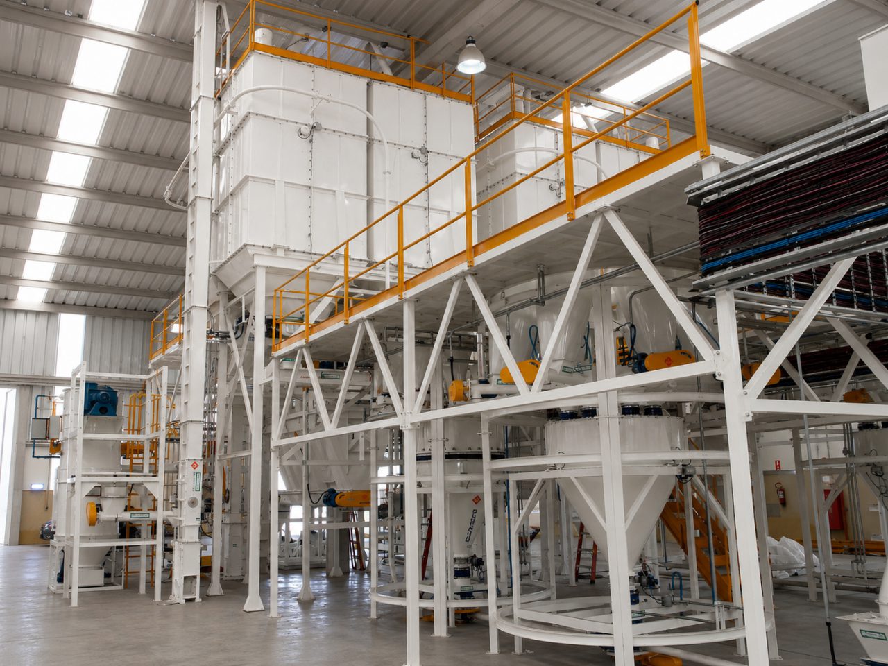 Instalación para la producción de núcleos vitamínicos, con tolvas de almacenamiento y plataforma de operación