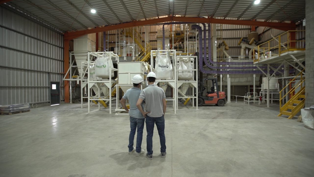 Dos operarios frente a la línea de elaboración de alimento balanceado porcino, en el interior de la planta